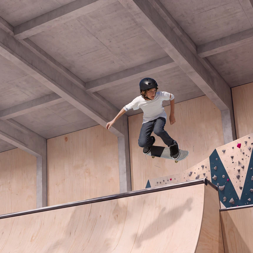 Helmeted skateboarder doing a trick in the air above an indoor ramp